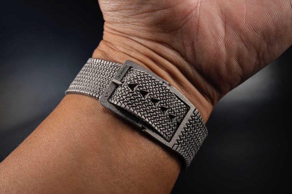 Essa pulseira de relógio é feita usando lasers; veja! Uma pulseira de relógio que busca combinar o conforto do tecido, a leveza da borracha e a resistência de um bracelete de metal foi apresentada recentemente pela marca independente da Malásia, Ming. Apelidada de Polymesh, a inovadora pulseira é fabricada por meio de um processo de impressão 3D a laser, utilizando titânio para criar uma peça que, segundo a empresa, oferece uma experiência única que reúne as melhores qualidades de diferentes materiais. Pulseira Polymesh da Ming