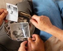 Pessoas olham fotografias antigas reunidas em um cesto