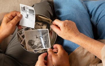 Pessoas olham fotografias antigas reunidas em um cesto
