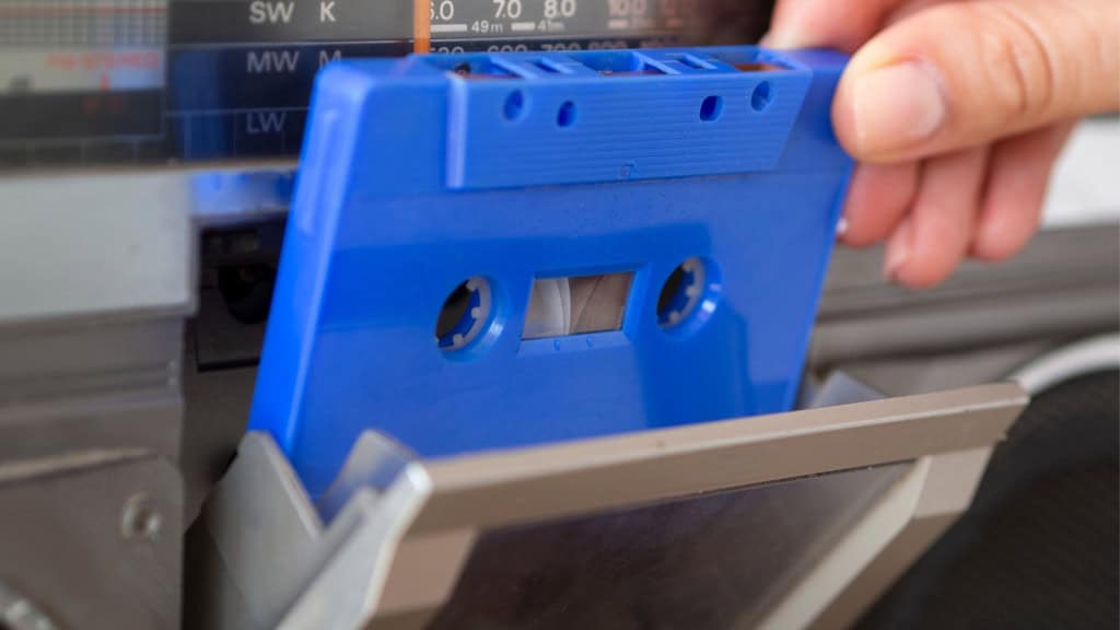 Pessoa colocando fita cassete azul no leitor de musica