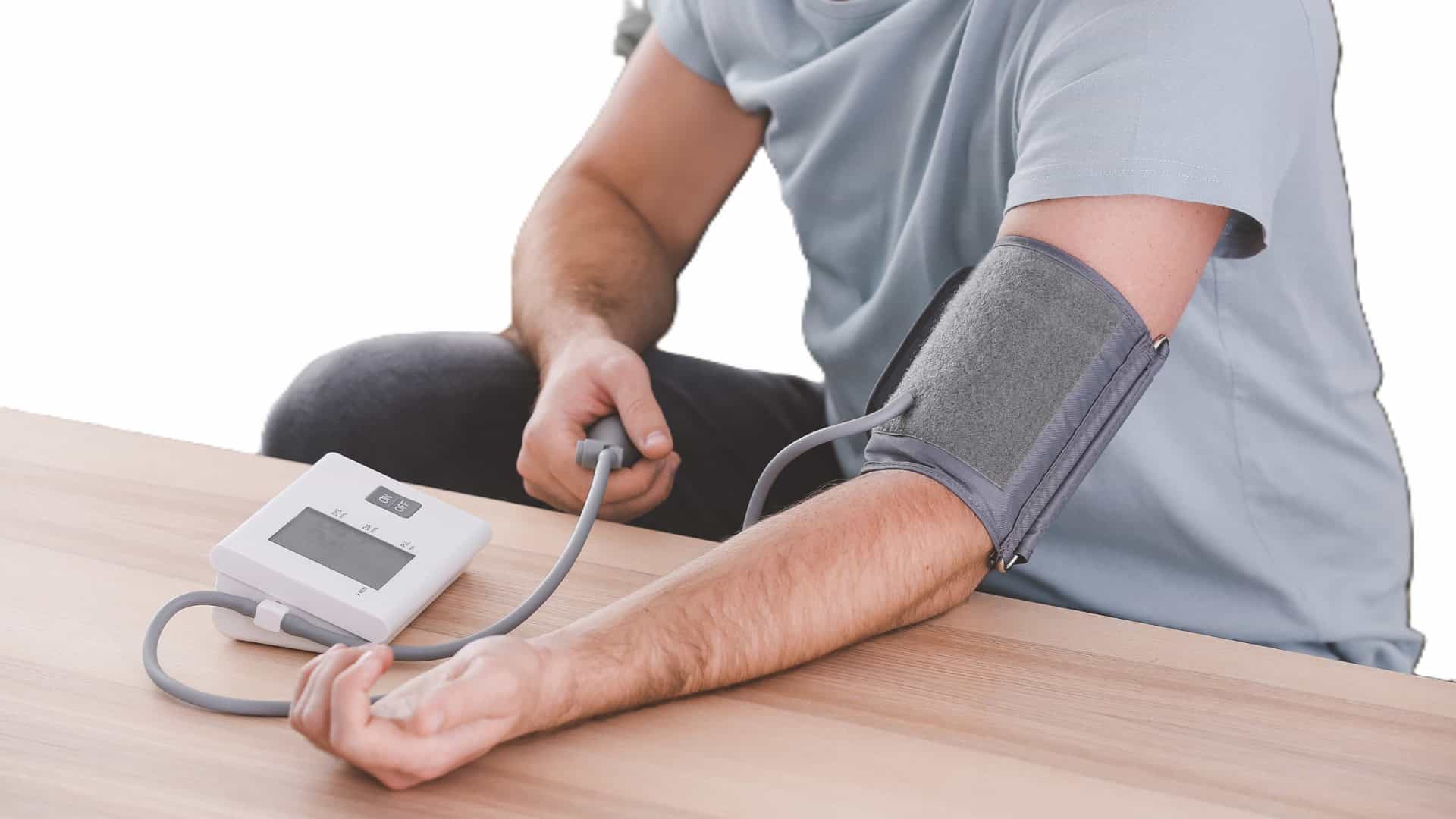 Pessoa medindo a pressão arterial em casa com aparelho digital no braço