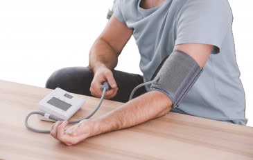 Pessoa medindo a pressão arterial em casa com aparelho digital no braço