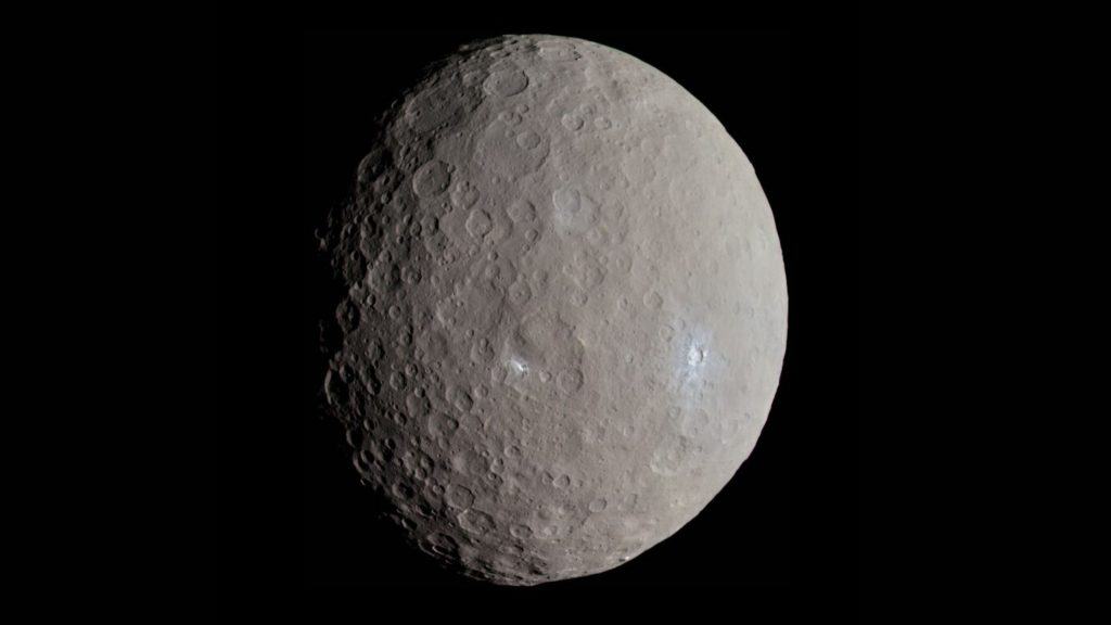 Qual a diferença entre asteroides, cometas e meteoros? O espaço está repleto de corpos celestes que viajam pelo Sistema Solar, e, às vezes, cruzam o caminho da Terra. Apesar de muitas pessoas confundirem os termos, asteroides, cometas e meteoros são objetos distintos, com origens, composições e comportamentos diferentes. Imagem de Ceres capturada pela sonda Dawn em 4 de maio de 2015, mostrando as crateras Haulani e Oxo, cujos materiais brilhantes lembram os da cratera Occator.