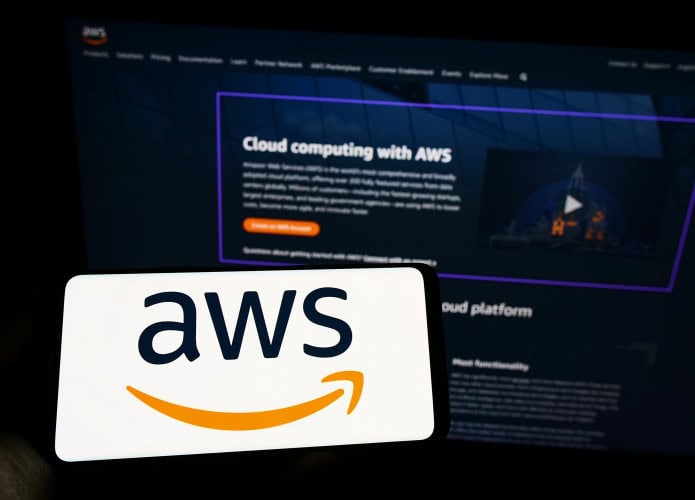 Ao fundo, site da AWS; à frente, smartphone na horizontal com o logo da AWS