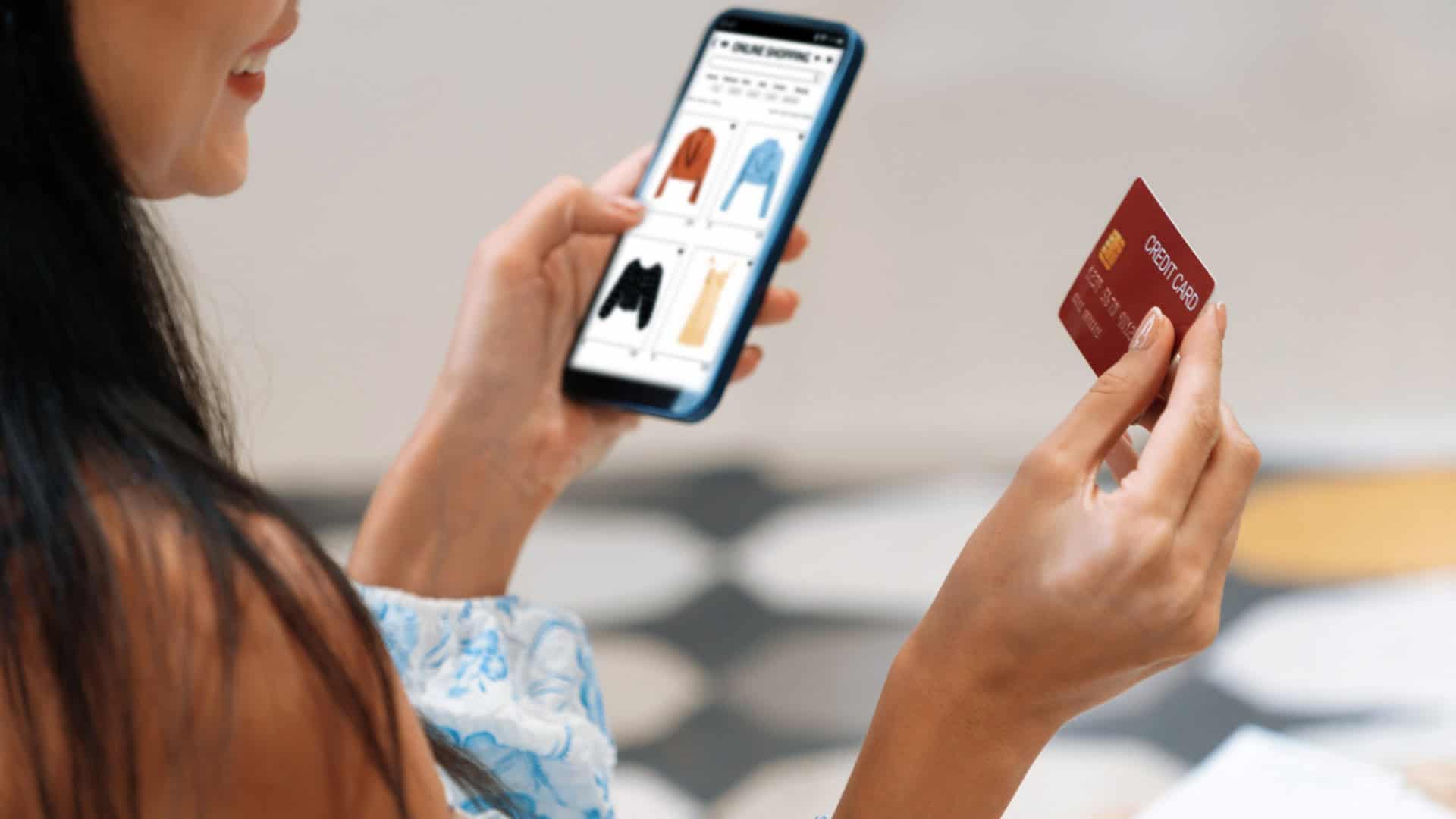 Mulher segurando com a mão esquerda e olhando para um smartphone e com um cartão na mão direita