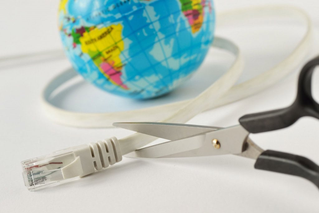 Imagem ilustrativa de tesoura cortando cabo de internet com planeta Terra