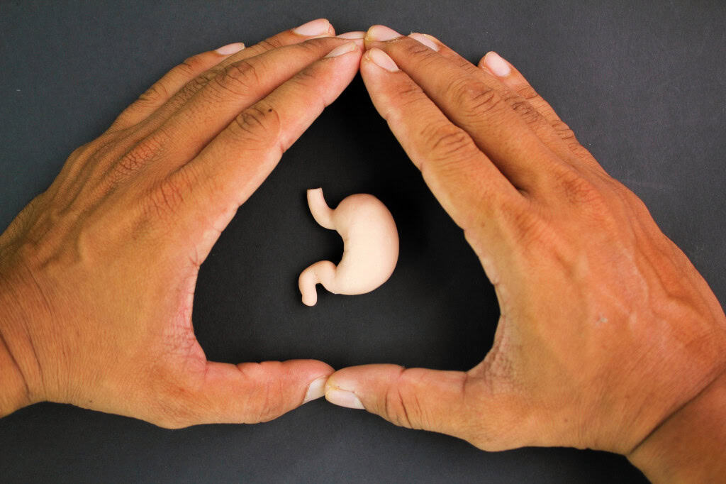 Pequeno estômago e duas mãos formando um triângulo ao redor