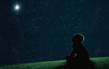 imagem mostra uma criança olhando para as estrelas a céu aberto