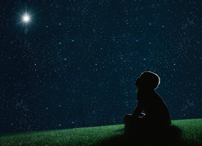 imagem mostra uma criança olhando para as estrelas a céu aberto