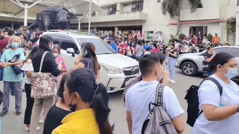 Pessoas cercando um carro e andando ao redor