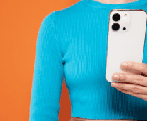 mulher segurando iphone com uma blusa azul e fundo laranja