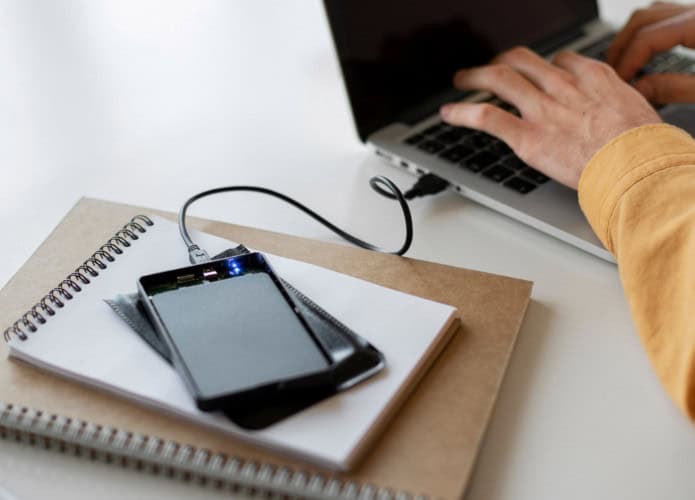 pessoa usando o notebook com um ssd externo conectado