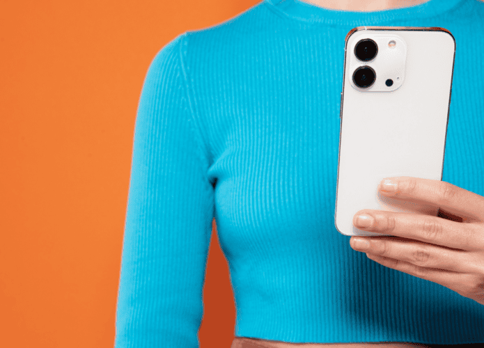 mulher segurando iphone com uma blusa azul e fundo laranja