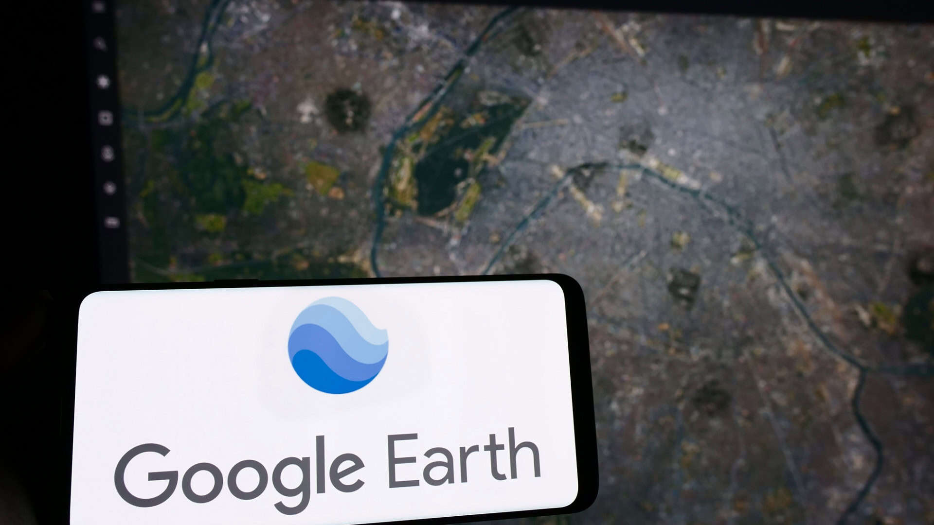 Ao fundo, mapa do Google Earth; à frente, logo do serviço em um smartphone na horizontal