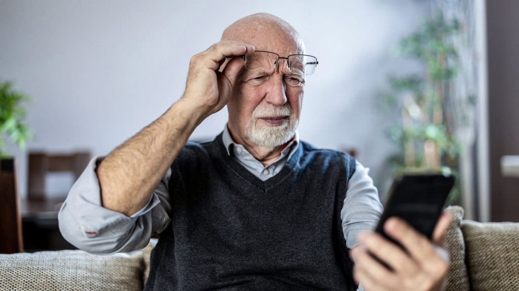 Homem idoso olhando confuso para o celular