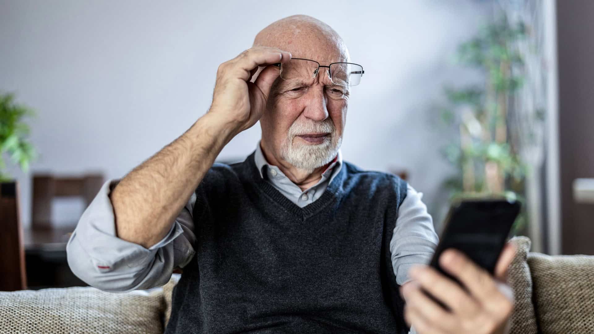 Homem idoso olhando confuso para o celular
