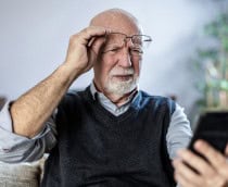Homem idoso olhando confuso para o celular