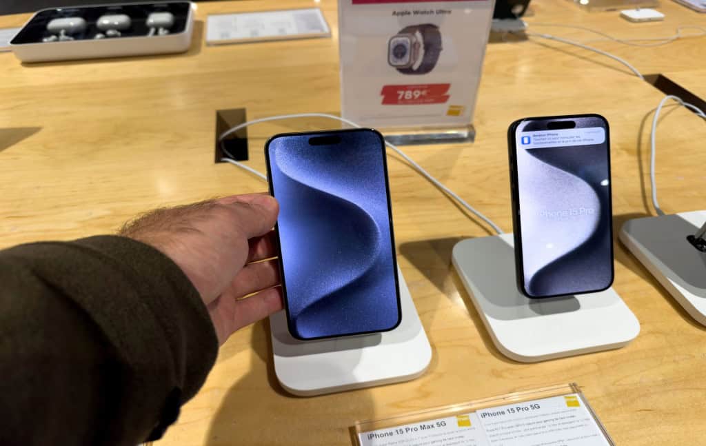 Imagem mostra uma mão masculina segurando um Apple iPhone 15 Pro Max exibe em detalhes seu corpo de titânio premium e a luxuosa tela OLED