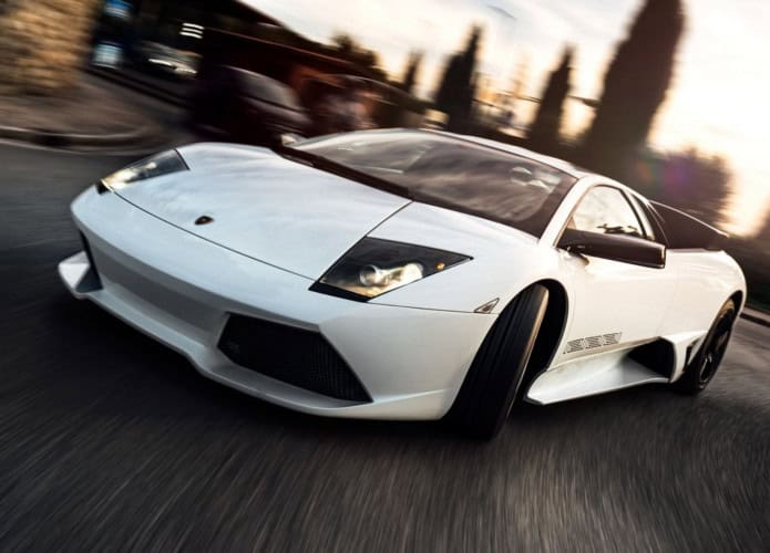 foto de um carro Murciélago branco da Lamborghini, em uma estrada de asfalto