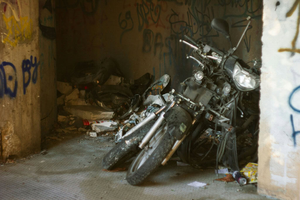 Imagem mostra uma moto abandonada e em ruínas, o que visualmente representa a deterioração e o fim que uma moto pode ter se for neglicenciada
