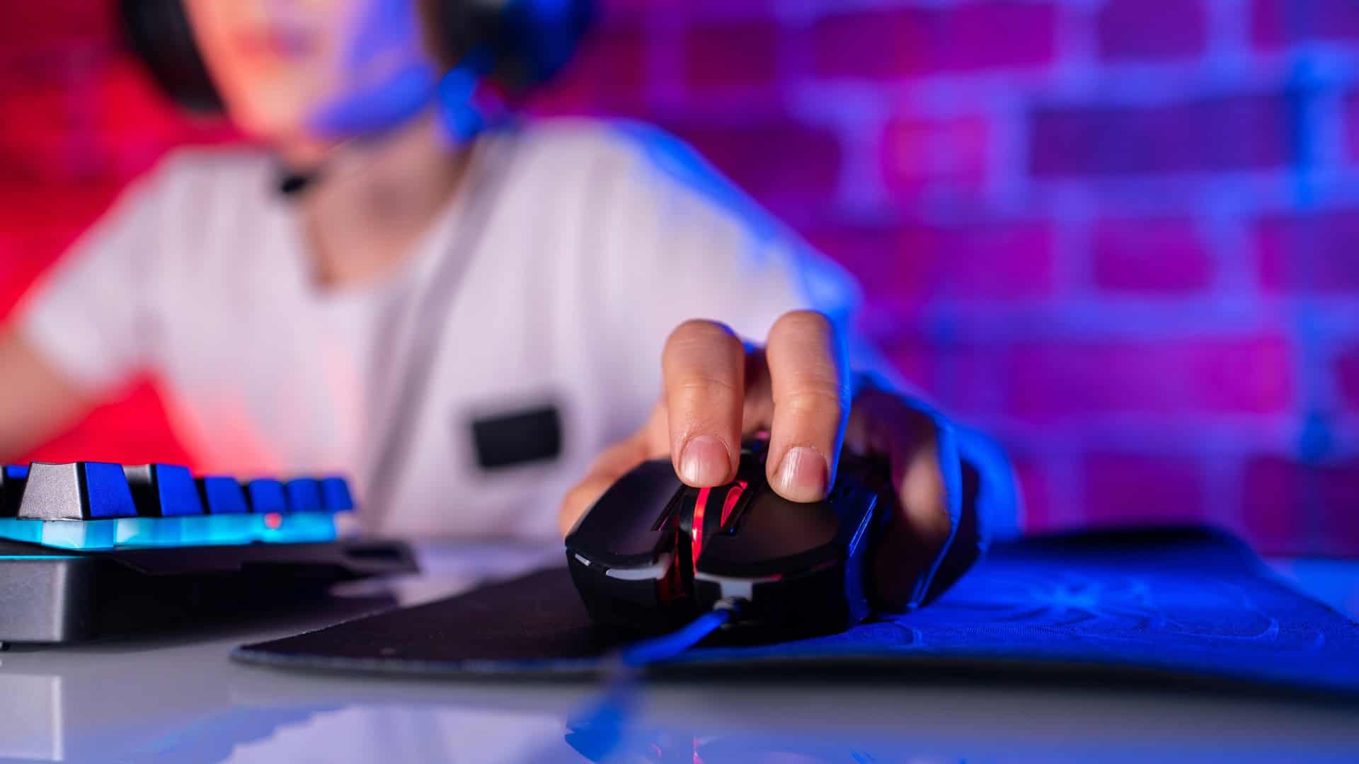 Close de garoto usando fone de ouvido e com a mão em um mouse