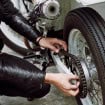 pessoa mexendo na corrente de sua motocicleta