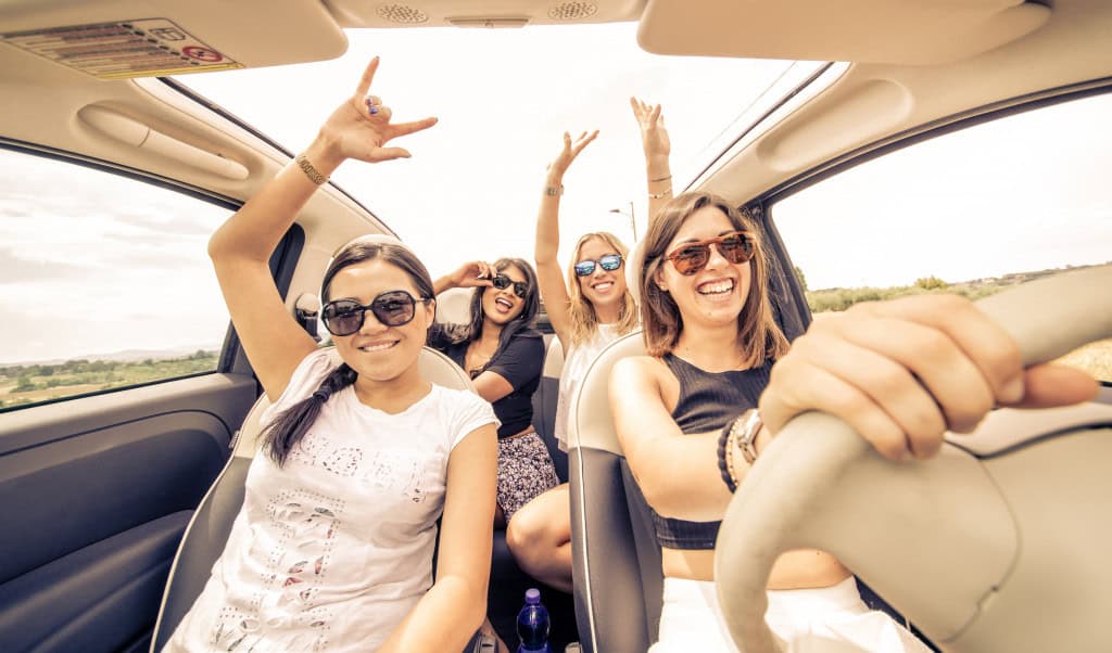 Quatro mulheres se divertem com música em um carro.