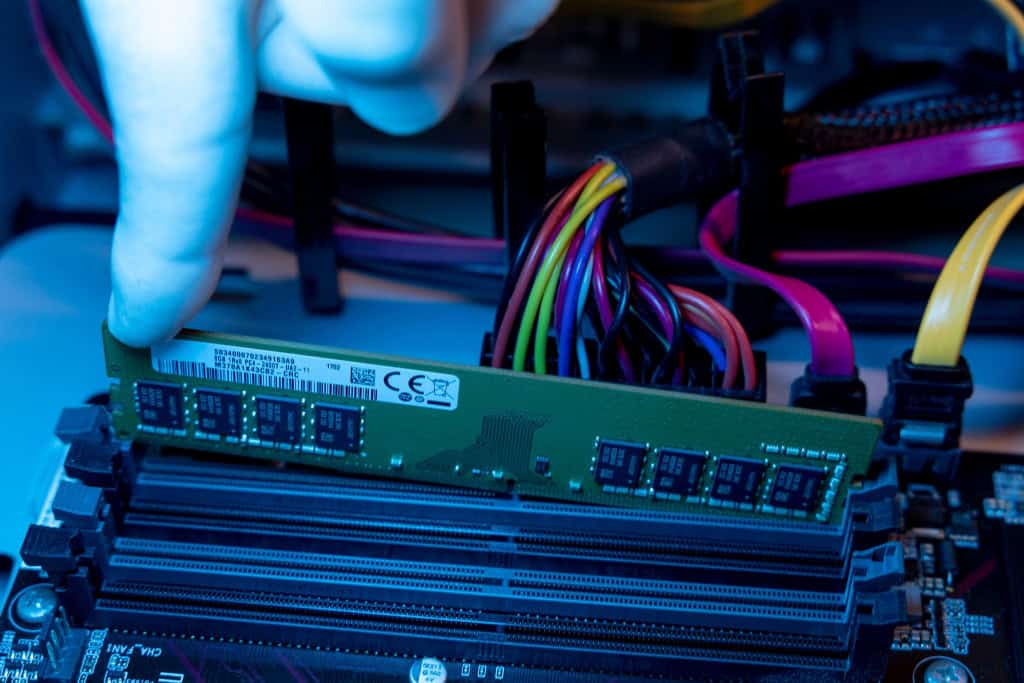Close da mão de um técnico com luvas instalando um slot de memória RAM