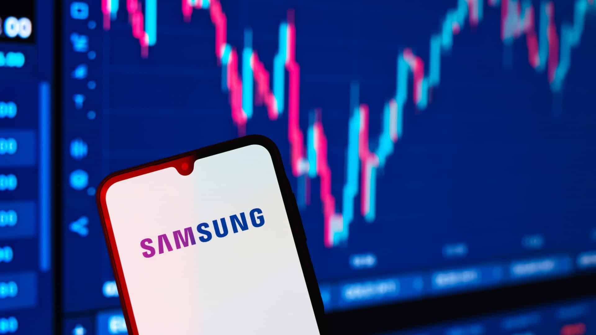 Ao fundo, gráficos financeiros; à frente, logo da Samsung em um smartphone
