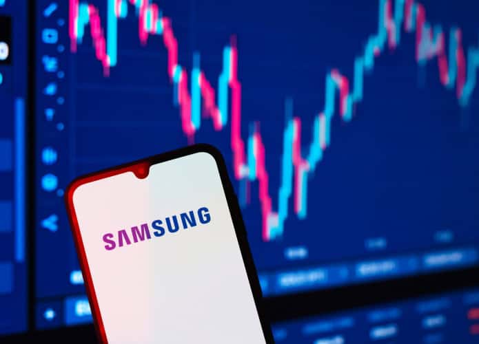 Ao fundo, gráficos financeiros; à frente, logo da Samsung em um smartphone