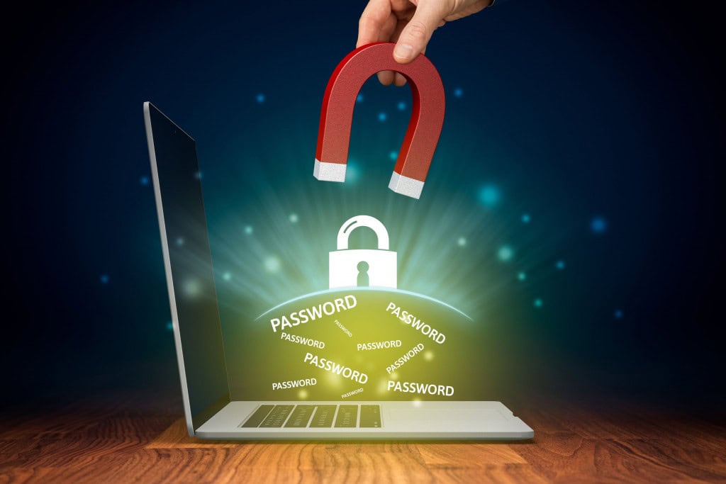 Imagem ilustrativa de mão com ímã roubando senhas por spyware de computador desprotegido