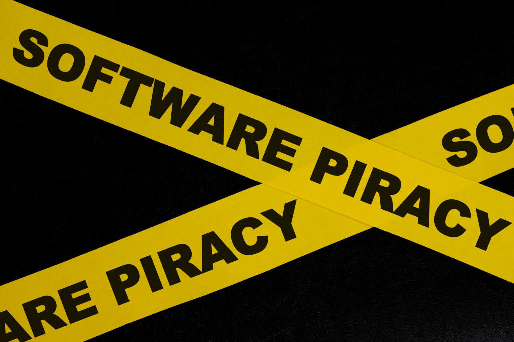 Fita de barreira amarela com palavra em fundo preto escuro sobre pirataria em softwares.
