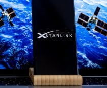 Logo da Starlink em um smartphone com satélites ao fundo