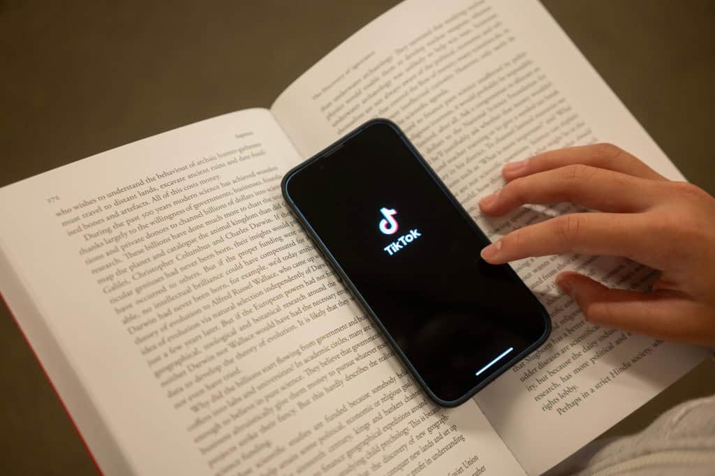 Smartphone com logo do TikTok em cima de um livro