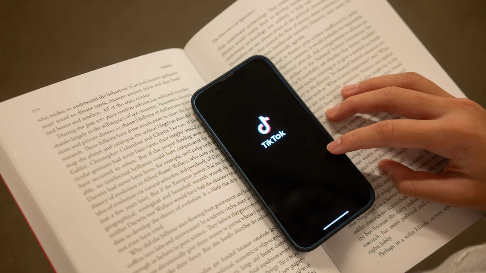 Smartphone com logo do TikTok em cima de um livro