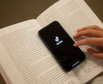 Smartphone com logo do TikTok em cima de um livro