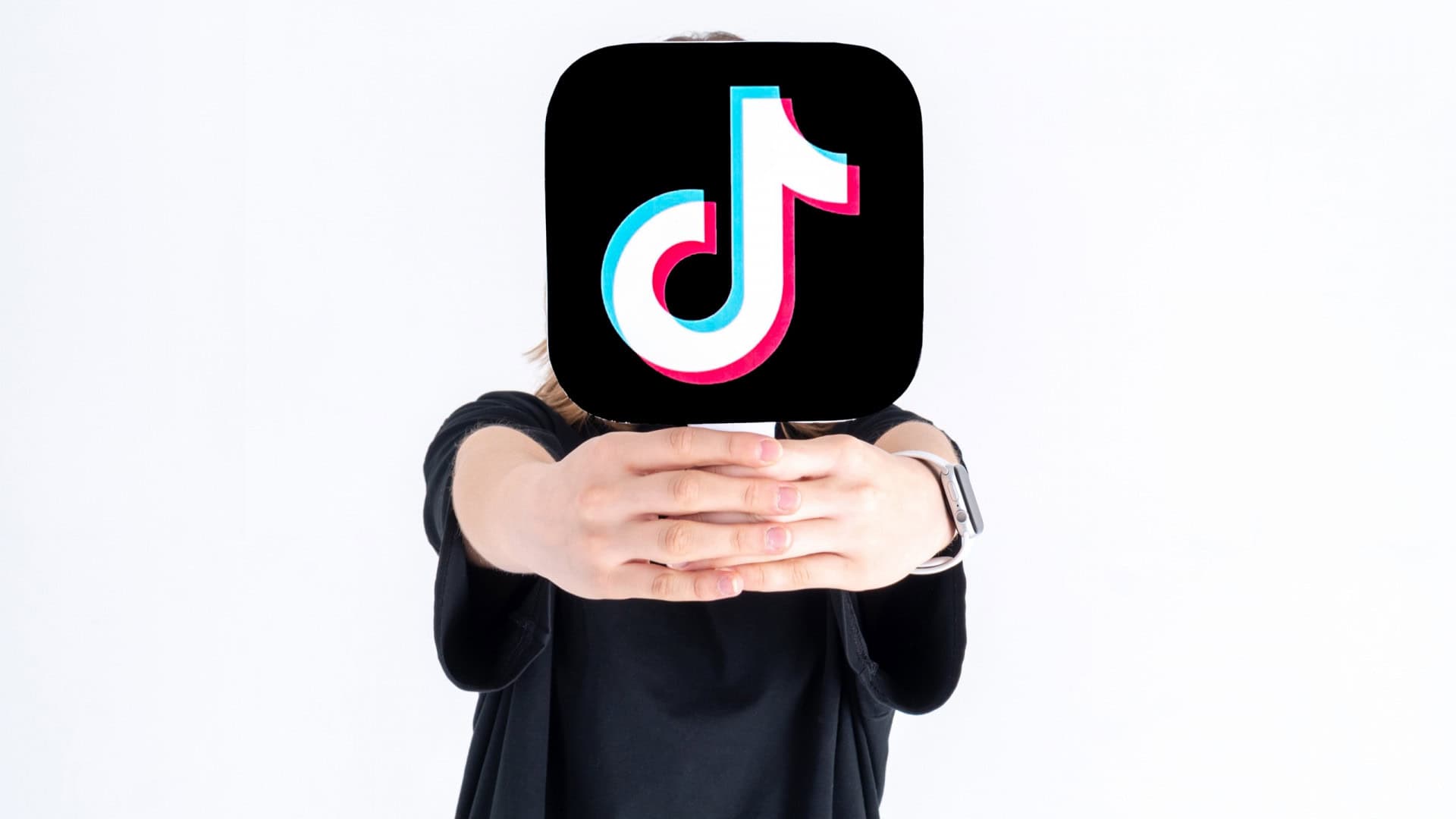 Pessoa segurando, à sua frente e cobrindo sua cabeça, uma placa com o logo do TikTok