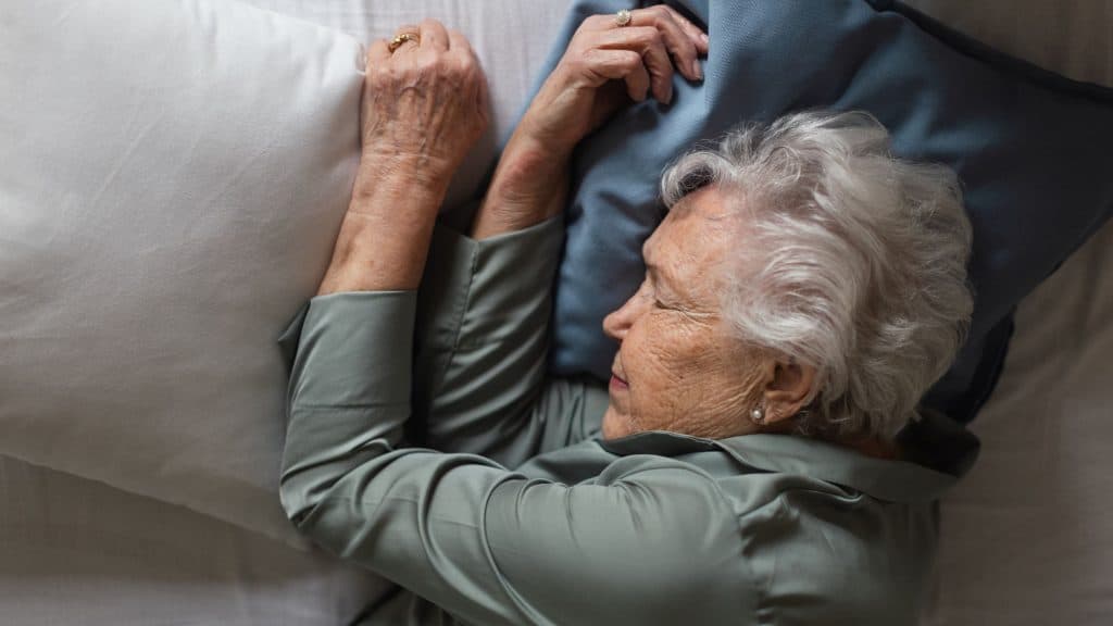 Mulher idosa dormindo em sua cama, vista superior