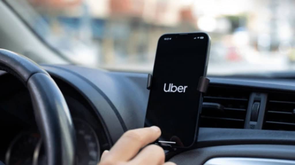 motorista da uber com o aplicativo aberto no celular dentro do carro