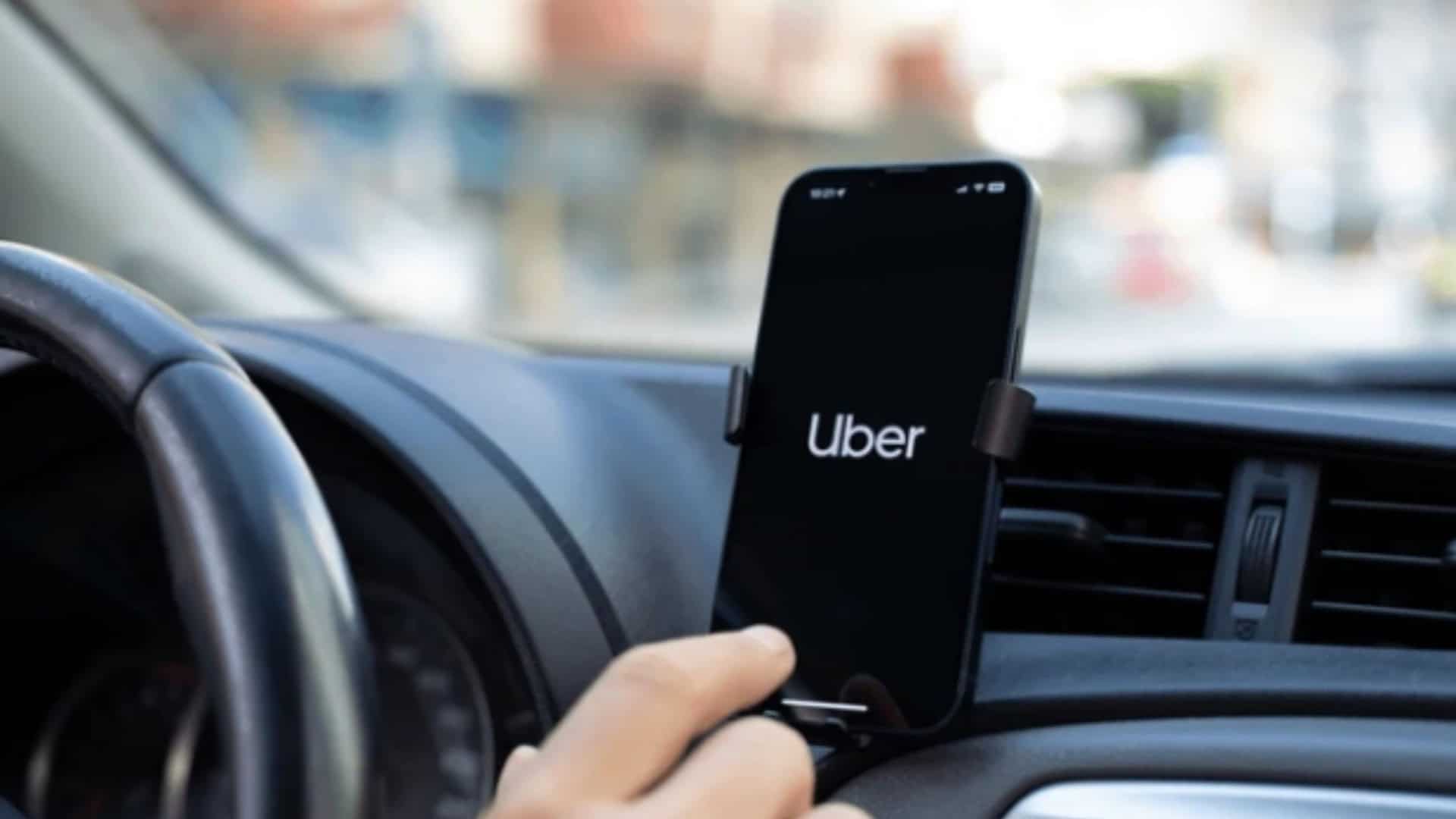 motorista da uber com o aplicativo aberto no celular dentro do carro