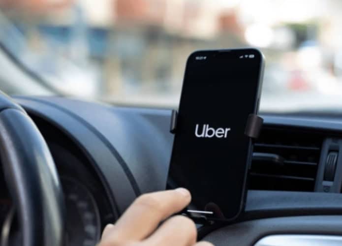 motorista da uber com o aplicativo aberto no celular dentro do carro