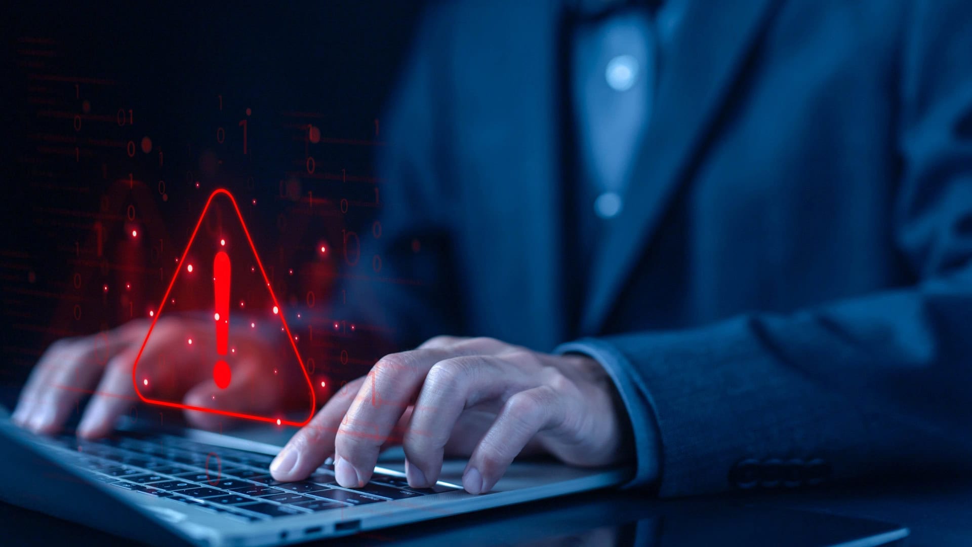 Pessoa digitando em um teclado de notebook com um sinal de alerta pairando sobre o teclado
