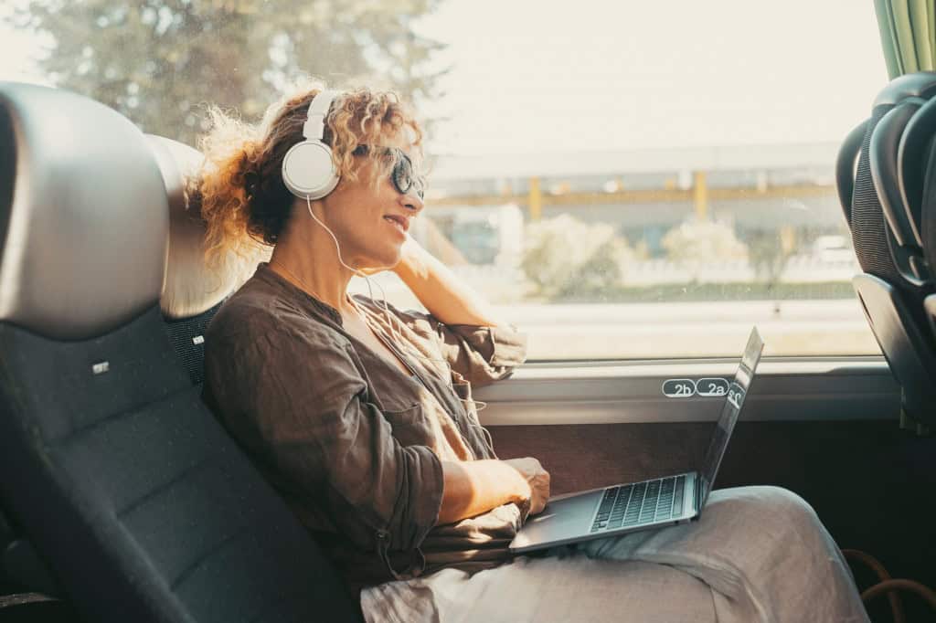 Mulher viagem de ônibus com fone de ouvide antiruído.