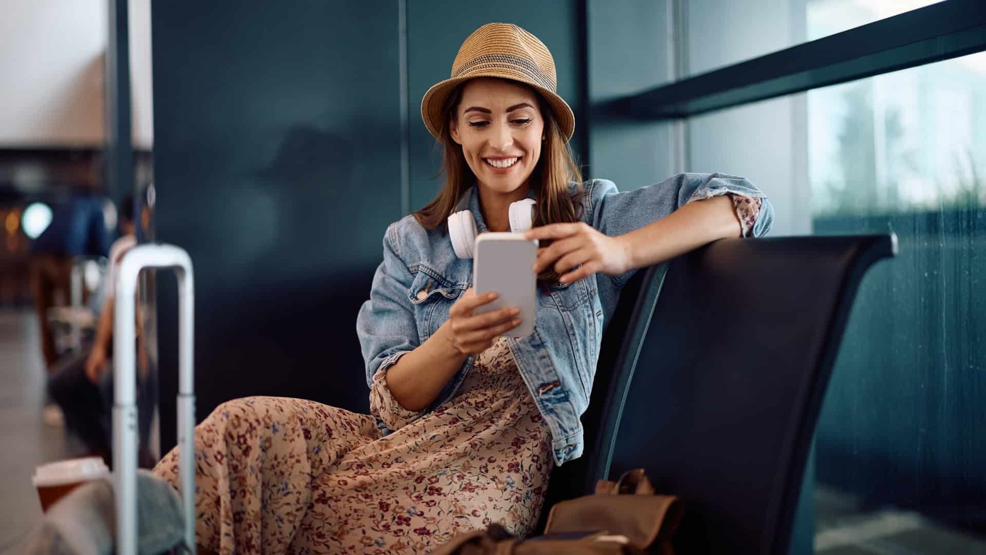 Mulher sorri ao usar o telefone na sala de espera do aeroporto.