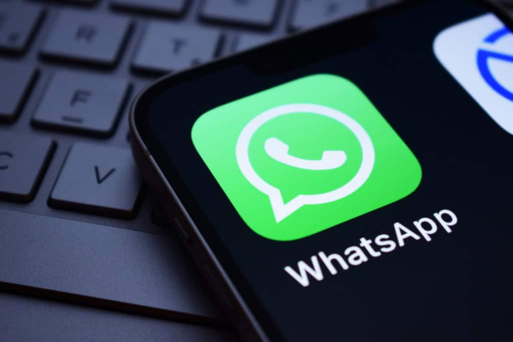Logo do app do WhatsApp na tela de um smartphone que está em cima de um teclado de notebook