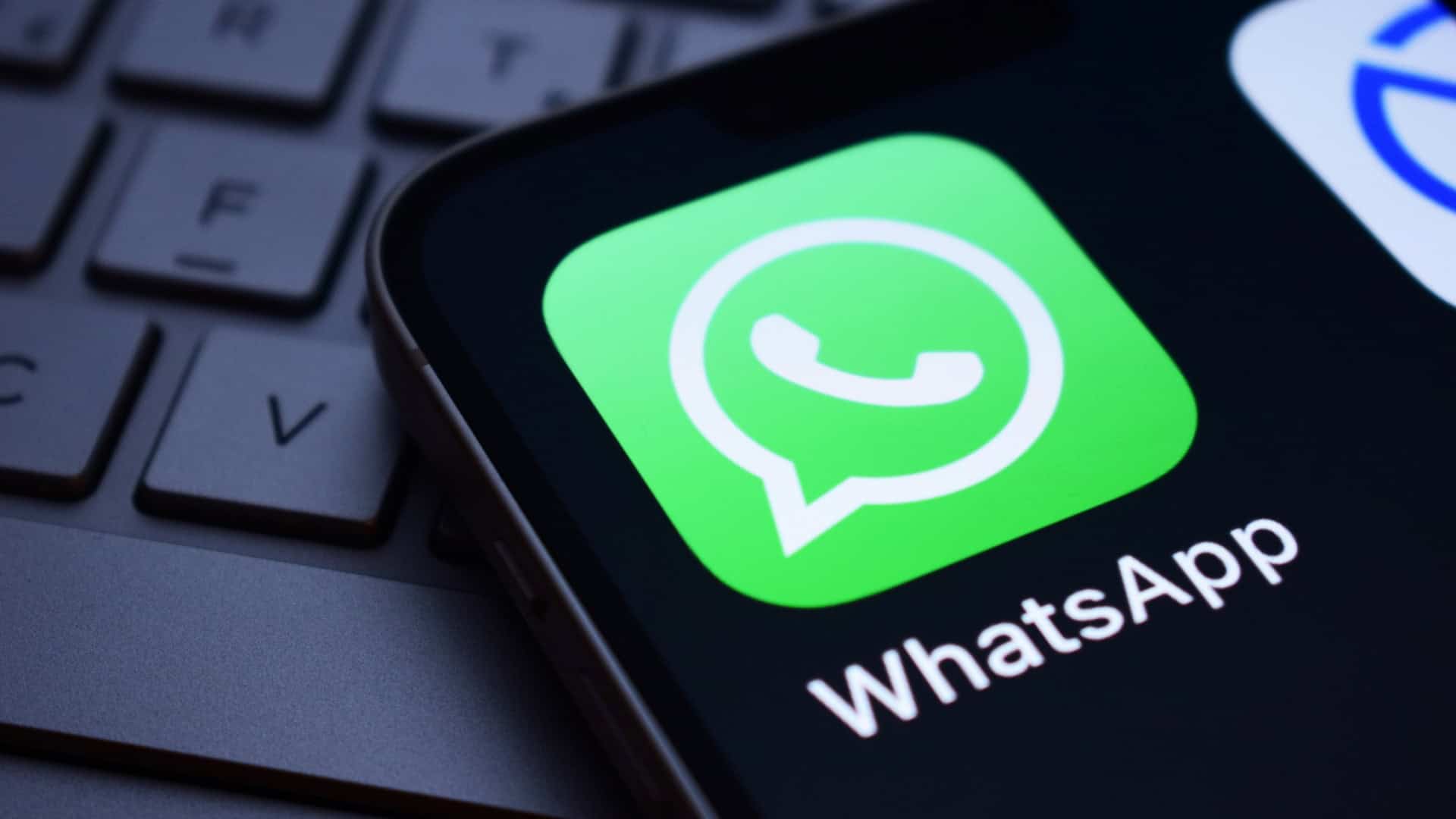 Logo do app do WhatsApp na tela de um smartphone que está em cima de um teclado de notebook