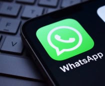 Logo do app do WhatsApp na tela de um smartphone que está em cima de um teclado de notebook