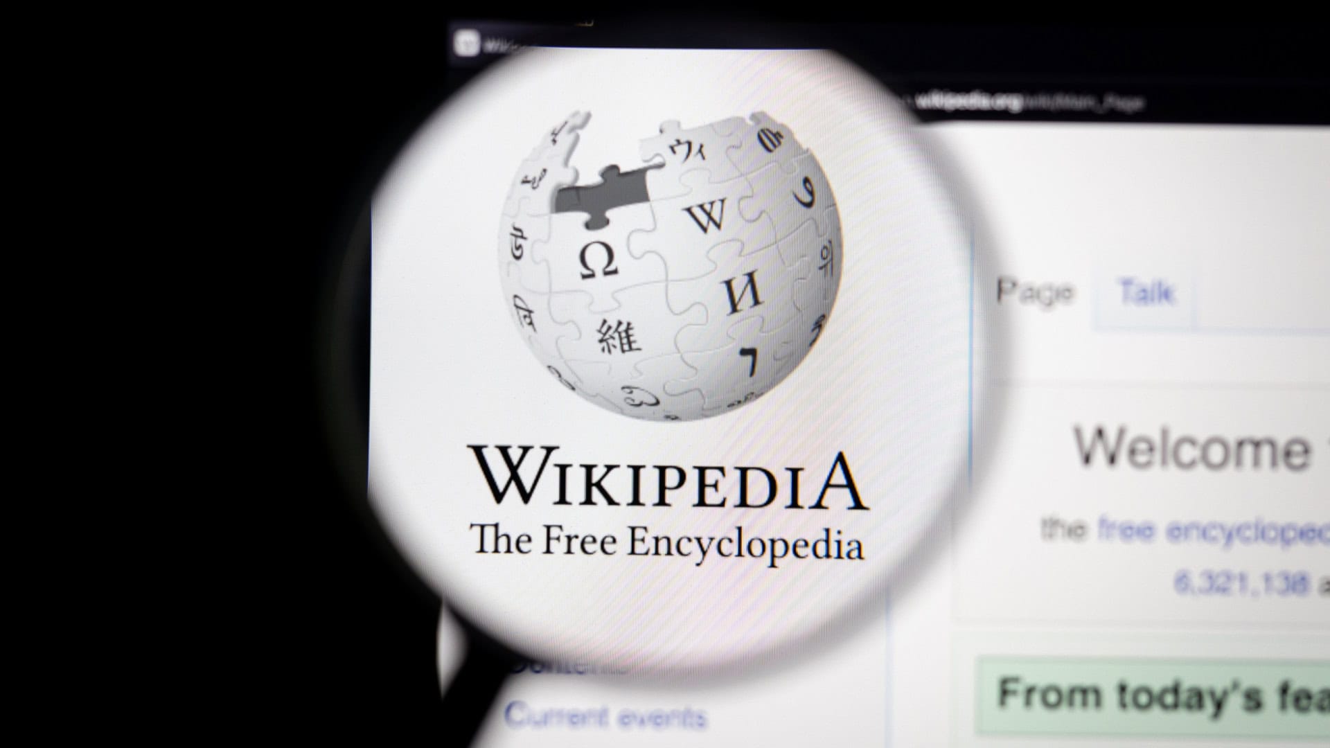 Logo do Wikipedia exibido em sua página oficial e ampliado por uma lupa