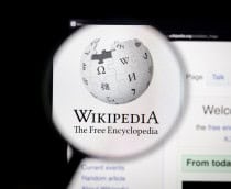 Logo do Wikipedia exibido em sua página oficial e ampliado por uma lupa