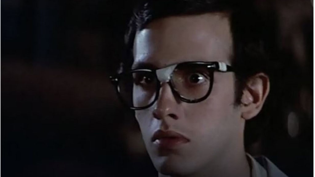 Jovem de óculos com um adesivo branco no meio, olhando assustado para algo